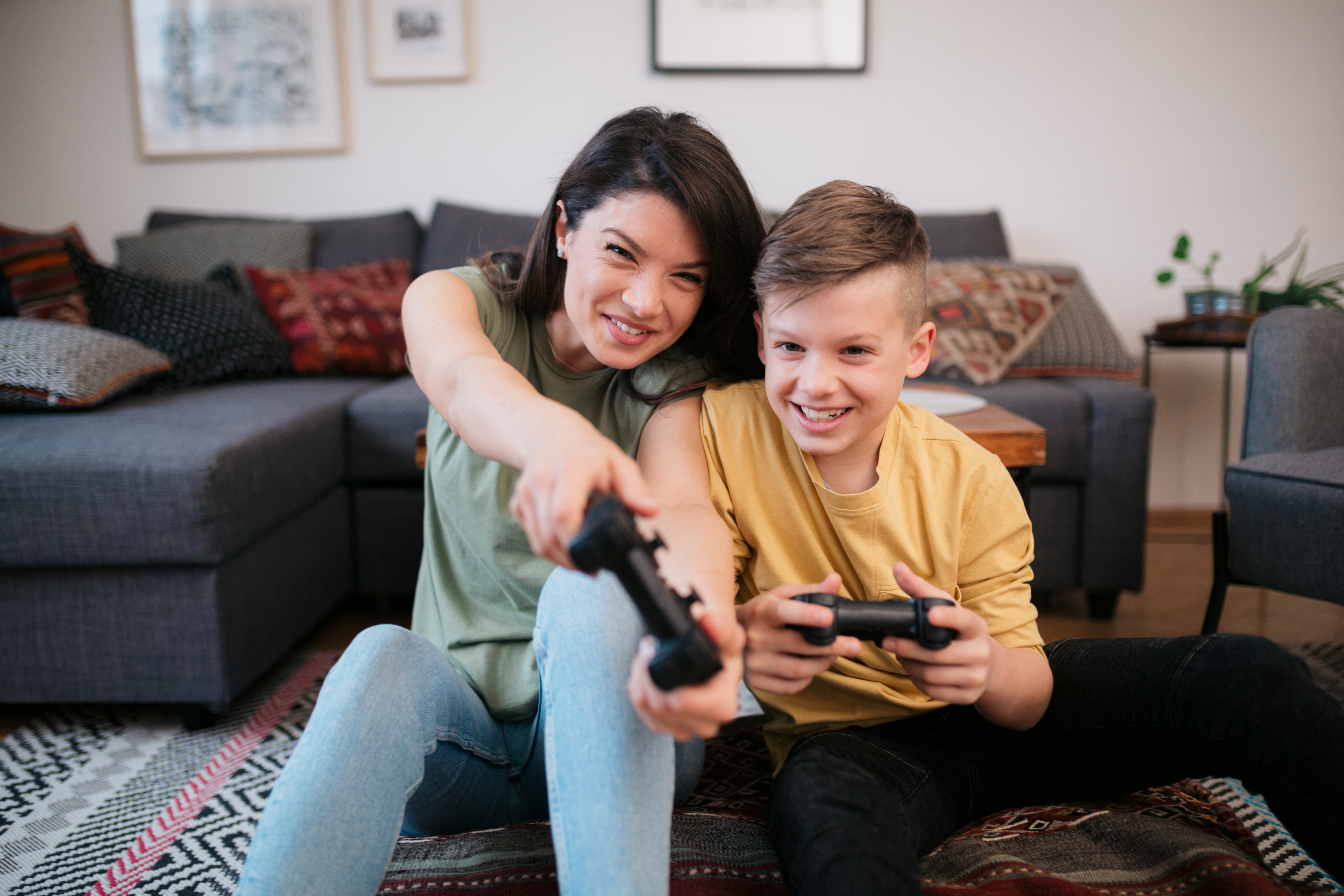 A parent and her son laughing together while playing video games at home